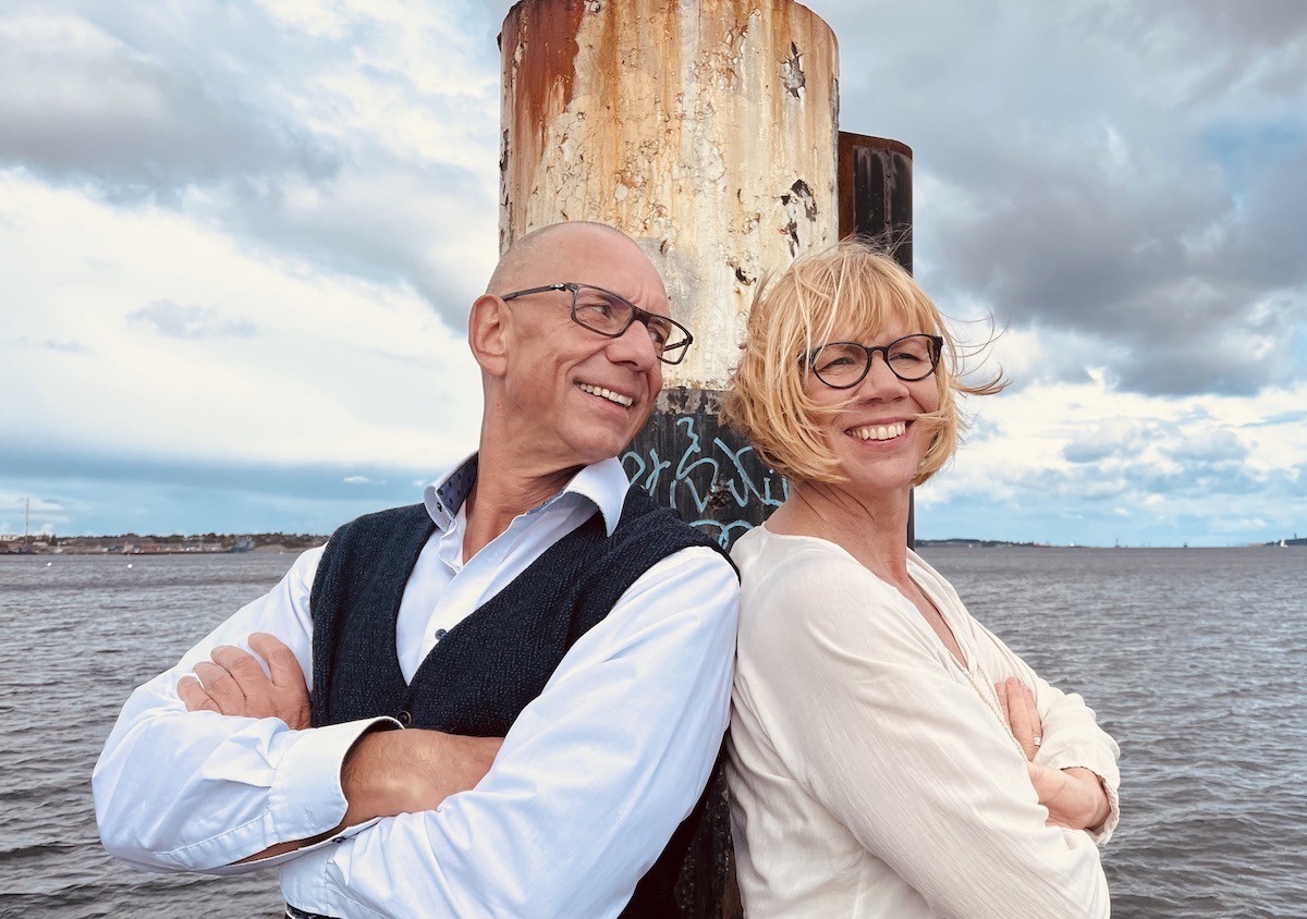 Das Team von keller ! consulting steht am Meer, angelehnt an einen Pfahl am Steg