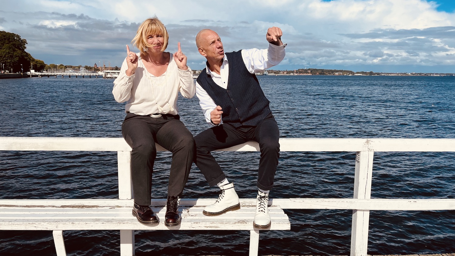 Das Team von keller ! consulting sitzt auf einem Steg am Meer und gestikuliert