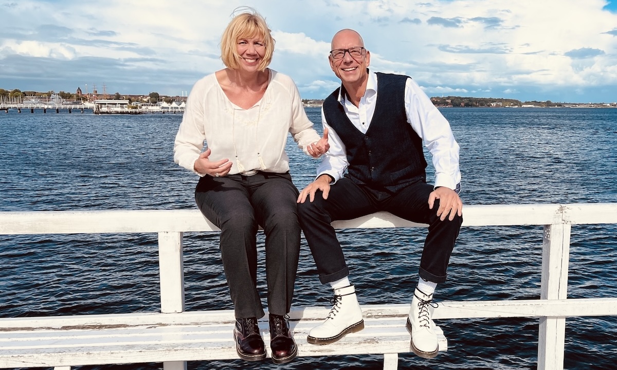 keller ! consulting • dörte stender + udo keller Das Team von keller ! consulting sitzt auf einem Steg am Meer und wirkt motivierend
